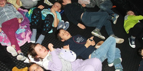 Powiększ grafikę: Dziewczynki i chłopcy z klasy 2a leżą na kocykach w mobilnym planetarium.