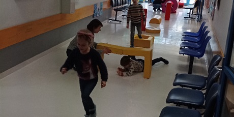 Powiększ grafikę: Zajęcia aktywizujące na korytarzu szkolnym z wykorzystaniem materacowych klocków. Zdjęcie przedstawia dzieci pokonujących tor przeszkód.