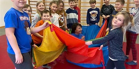 Powiększ grafikę: Uczniowie podczas zabaw aktywizujących z wykorzystaniem kolorowej chusty Klanzy.