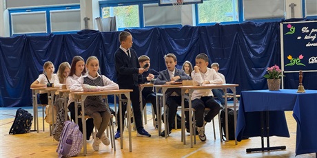 Powiększ grafikę: Chłopiec z klasy 5a przechadza się między uczniami, prowadząc część uroczystości.