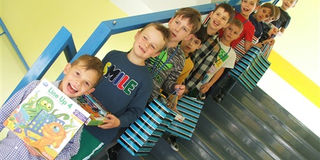 Powiększ grafikę: Chłopcy stoją na schodach z otrzymanymi prezentami. 