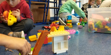 Powiększ grafikę: Dzieci konstruują budowle z klocków lego.