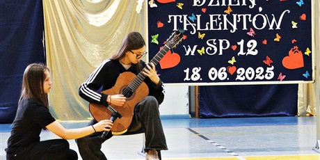 Powiększ grafikę: Uczennica gra na gitarze.
