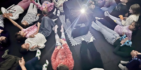 Powiększ grafikę: Uczniowie leżący na macie w Kinie sferycznym.