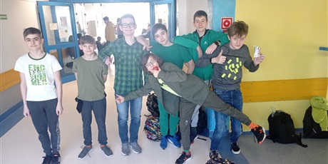 Powiększ grafikę: Chłopcy z klasy siódmej, ubrani na zielono, pozują do zdjęcia na korytarzu szkolnym.