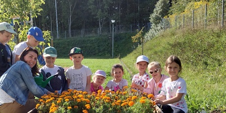 Powiększ grafikę: Zdjęcie grupowe uczniów z klasy 02 na tle rabatek kwiatowych. 