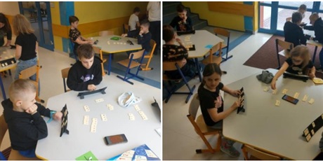 Powiększ grafikę: Uczniowie grają w grę Rummikub przy stolikach.