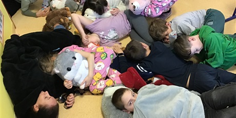 Powiększ grafikę: Uczniowie leżą wtuleni w swoje przytulanki.