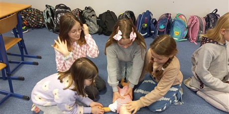 Powiększ grafikę: Dziewczynki z klasy 3d uczą się wykonywać masaż serca na fantomie niemowlęcia.