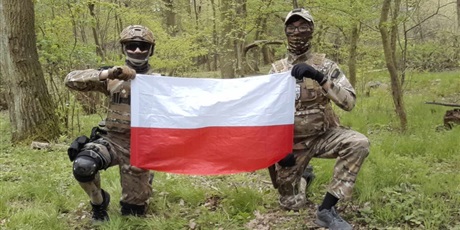Powiększ grafikę: Chłopcy przebrani w strój wojskowy trzymający flagę Polski.