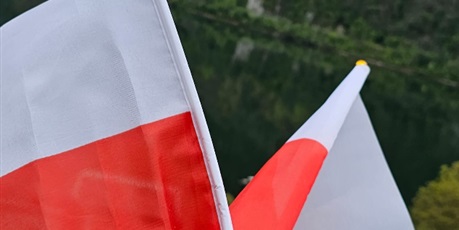Powiększ grafikę: Dwie flagi Polski na tle jeziora.