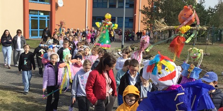 Powiększ grafikę: Uczniowie maszerują wokół szkoły z marzannami.